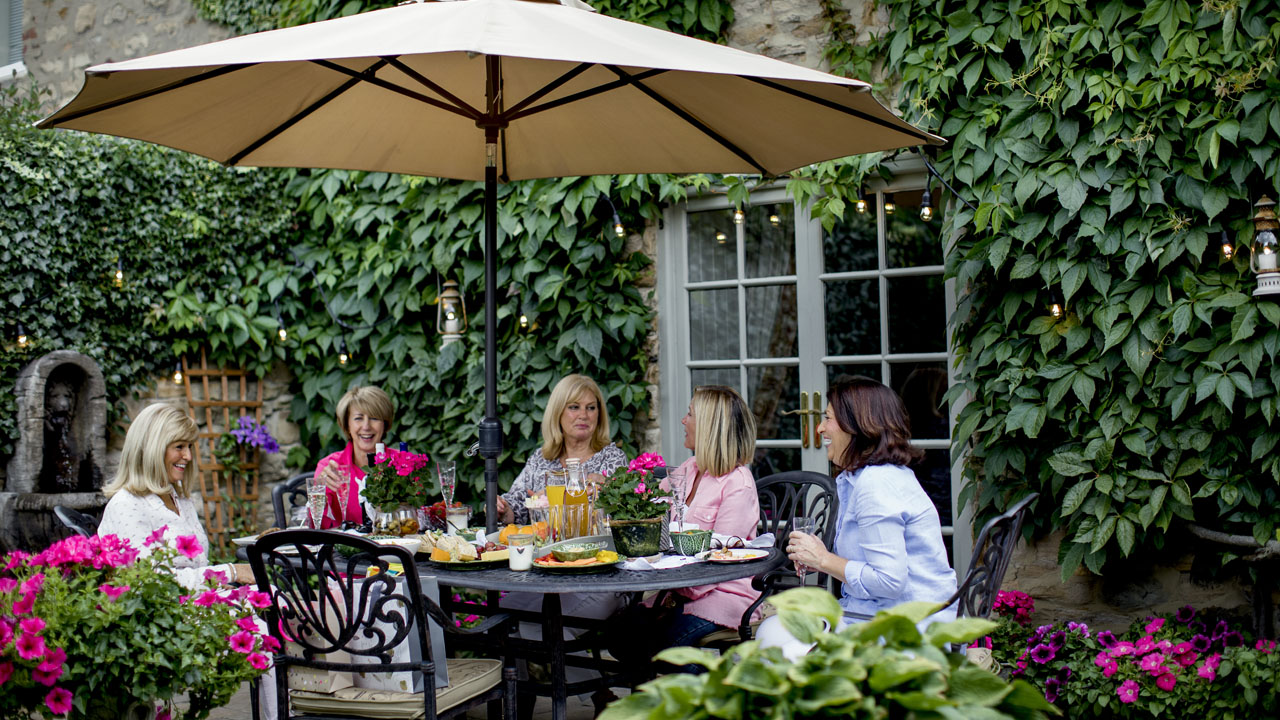 Five women having a conversation in a garden area